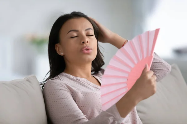 Unhealthy biracial woman breathe fresh air from hand fan — Stock Photo, Image