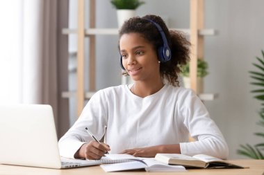 Kulaklık takan Afrikalı bir kız Skype öğretmeniyle laptopta ders çalışıyor.