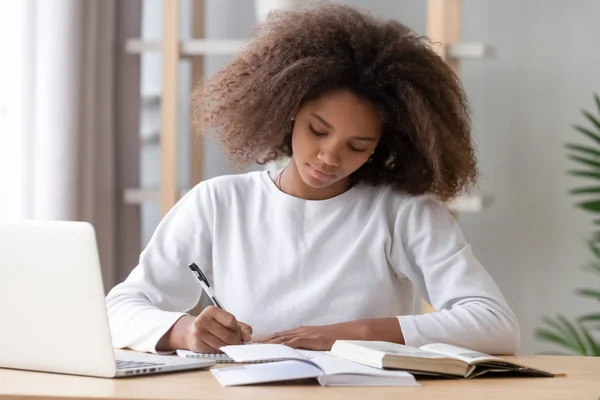 Focalizzato africano americano scuola ragazza studiare scrittura saggio facendo i compiti a casa — Foto Stock