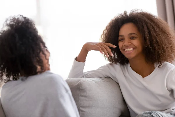 Happy african mother and daughter talking laughing sitting on sofa — Stock Photo, Image