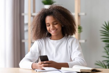Mutlu Afrikalı genç kız kitaplarla çalışan telefon uygulaması kullanıyor.