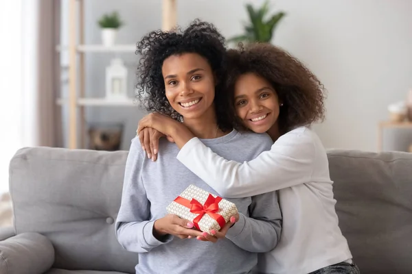 Happy african teen daughter congratulating mom hugging looking at camera — Stock Photo, Image