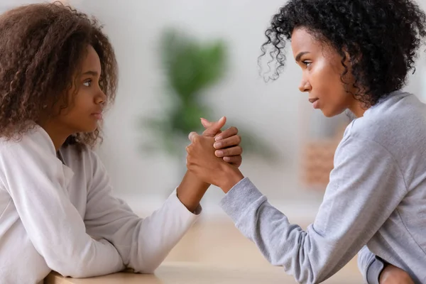 Serious african american mom and teen daughter arm wrestling — Stock Photo, Image