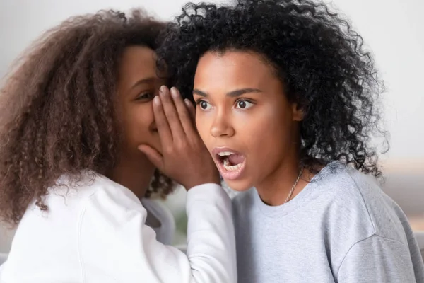 Africano americano adolescente filha sussurrando no ouvido mãe dizendo segredo — Fotografia de Stock