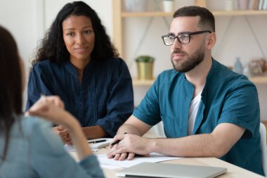 Genç iş başvurusunu dinleyen odaklanmış karışık ırk insan kaynakları yöneticileri.