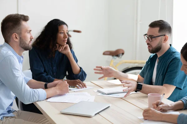 Pensiv blandras lagkamrater diskuterar projektdetaljer. — Stockfoto