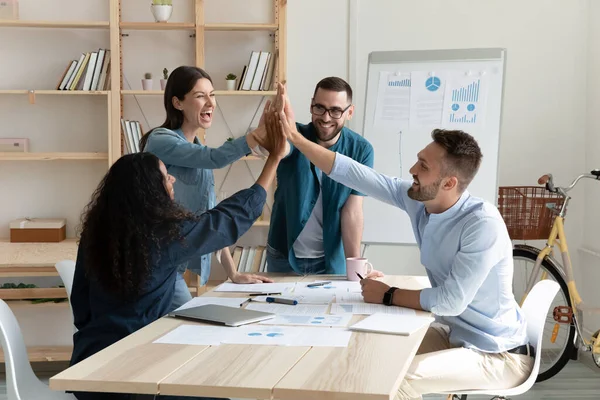 Overjoyed young mixed race employees celebrating shared business success. — Stock Photo, Image