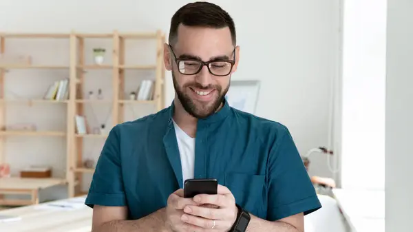 Jong lachend bedrijf werknemer op zoek naar mobiele telefoon scherm. — Stockfoto