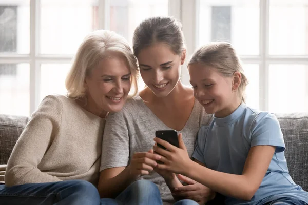 Щасливі три покоління, які дивляться на мобільний екран . — стокове фото