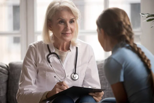 Middle aged pleasant pediatrician listening to young patient complaint.