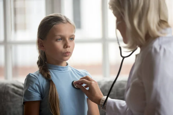 Yetişkin bir çocuk doktoru kalp atışlarını dinlerken kız öğrenci derin nefes alıyor.. — Stok fotoğraf