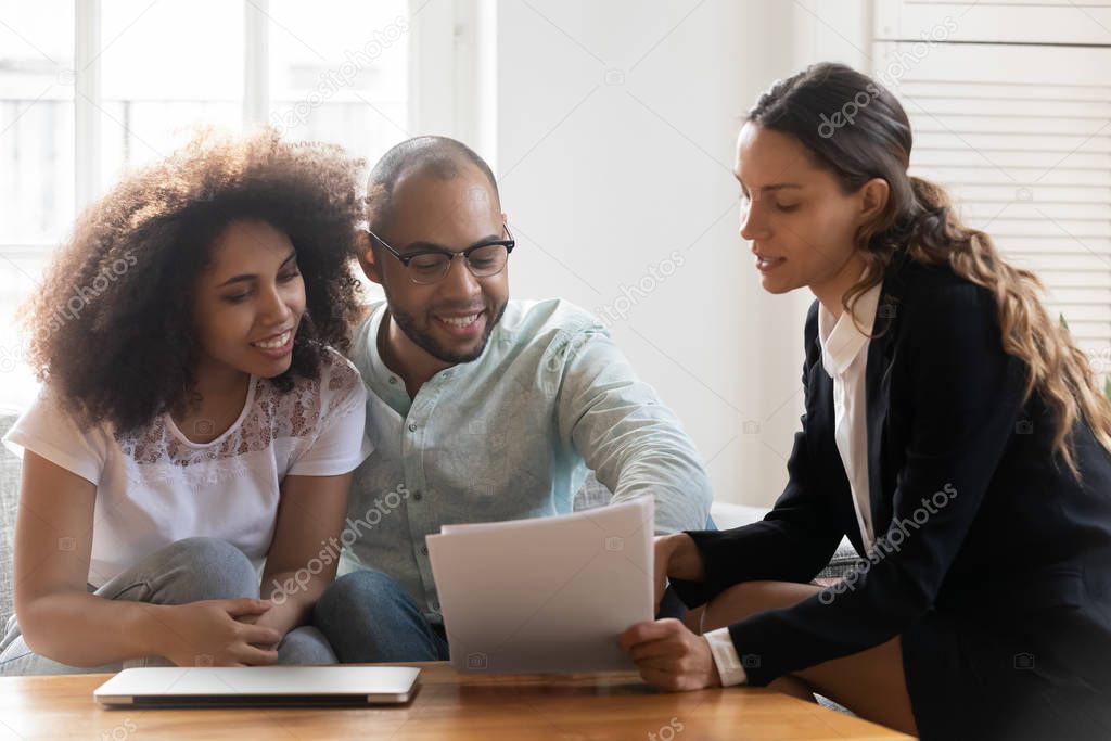 Mixed-race couple discussing contract terms during meeting with realtor