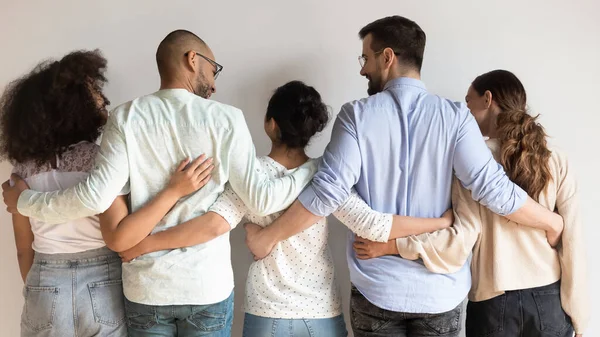 Rear view multiethnic best friends embracing standing near grey wall — Stock Photo, Image