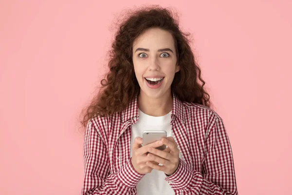 Positively shocked happy millennial girl holding mobile phone, feeling amazed. — Zdjęcie stockowe