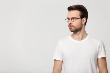Serious concentrated young guy standing aside free copy space.