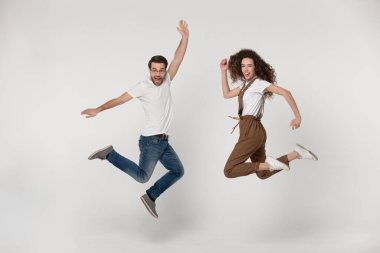 Full length joyful young man and happy woman jumping high.