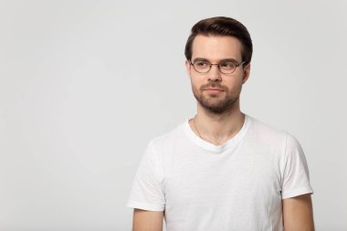 Thoughtful young confident man wearing eyeglasses standing aside copy space.