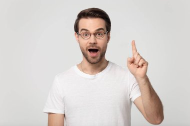 Surprised happy millennial man rising finger up on empty copyspace.