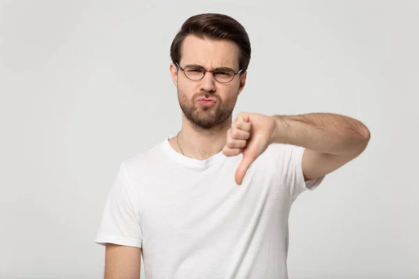Head shot millennial guy in eyeglasses showing thumbs down gesture. — Stock Photo, Image