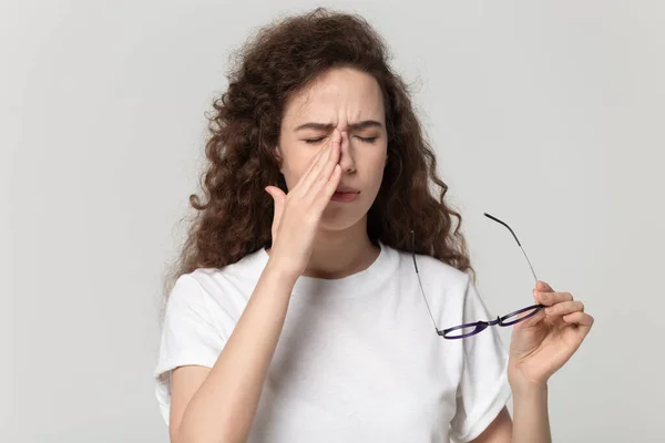 Mujer joven cansada cayendo gafas, que sufre de síndrome de ojos secos . — Foto de Stock