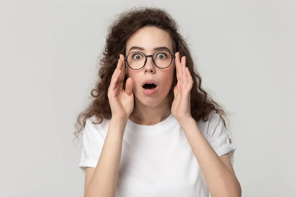 Negatively surprised young woman in eyeglasses looking closely at camera. — Stockfoto
