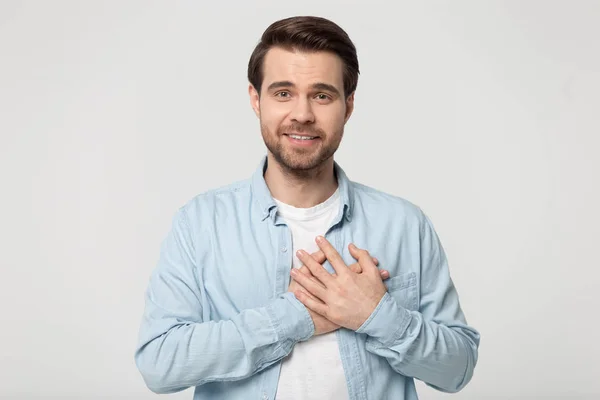 Grateful millennial guy folded hand on chest near heart. — Stockfoto