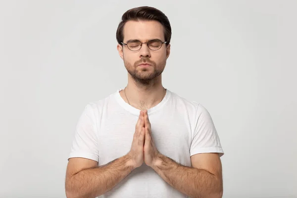 Hopeful young man in glasses praying to God. — Stockfoto