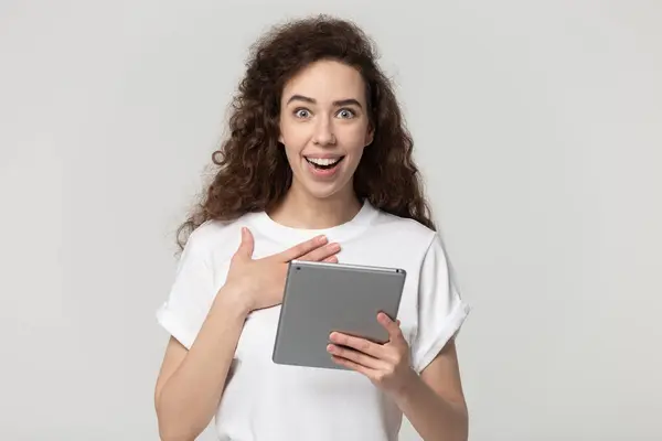 Surprised young woman holding digital tablet in hands. — Zdjęcie stockowe