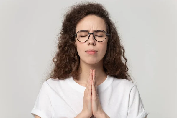 Atractiva joven en gafas rezando con las manos dobladas . —  Fotos de Stock