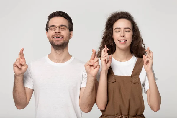 Superstitious happy guy and girl standing with crossed fingers. — Zdjęcie stockowe