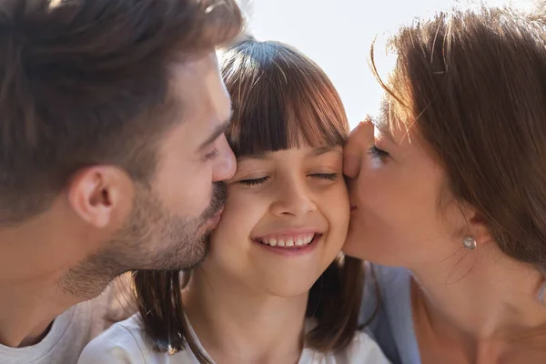 Close up of loving parents kiss small daughter on cheeks — Stock Photo, Image
