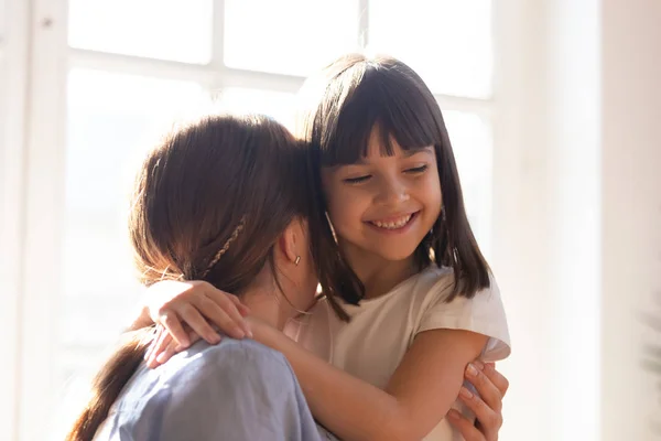Милая маленькая девочка обнимает молодую маму показывая любовь — стоковое фото