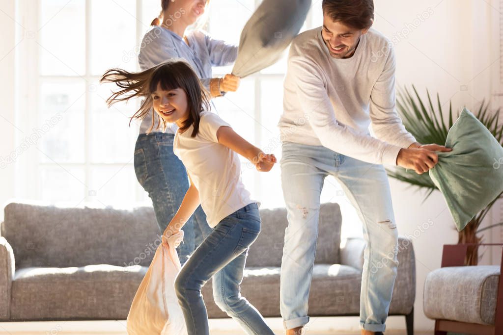 Playful parents engaged in pillow fight with little daughter