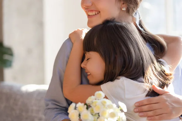 Amoroso pequena filha abraço mamãe saudação apresentando flores — Fotografia de Stock