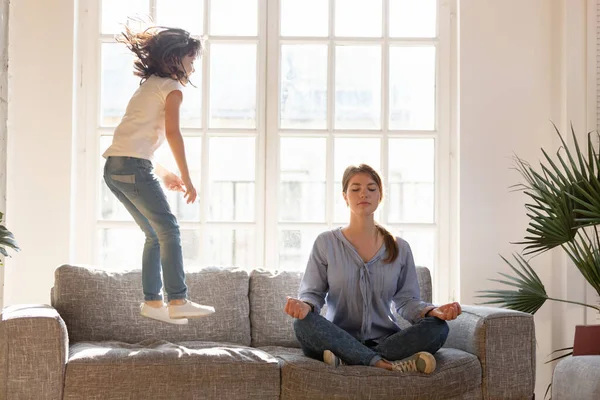Mom meditating on couch ignore kid jumping near — Stock Photo, Image