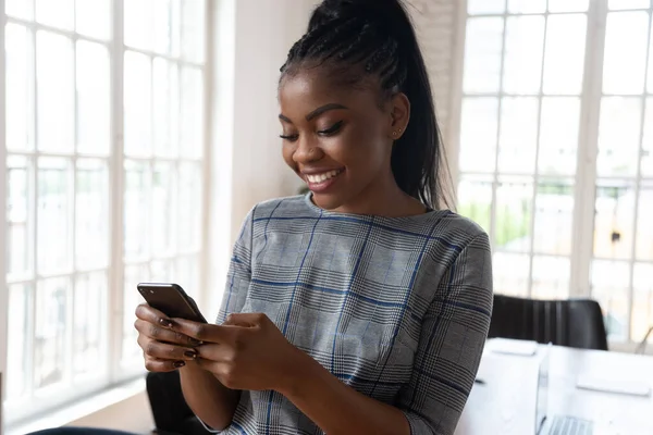 Closeup attractive african businesswoman with smartphone at workplace — Stock Photo, Image