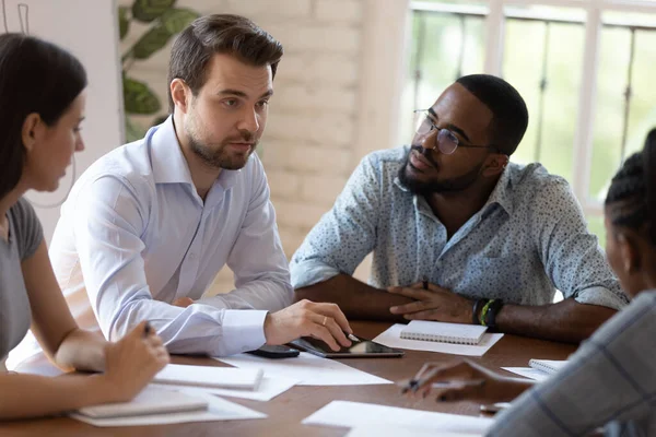 Ocupados empleados diversos escuchando entrenador europeo en la reunión del grupo — Foto de Stock