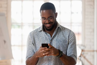 Afrikalı adam uygulamaları kullanarak telefon tutuyor. İş günü ara veriyor.