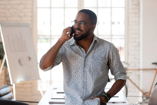Hombre de negocios africano hablando por teléfono dentro de la oficina moderna —  Fotos de Stock