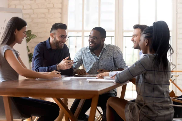 Diverse medewerkers zitten aan tafel en hebben een prettig positief gesprek — Stockfoto