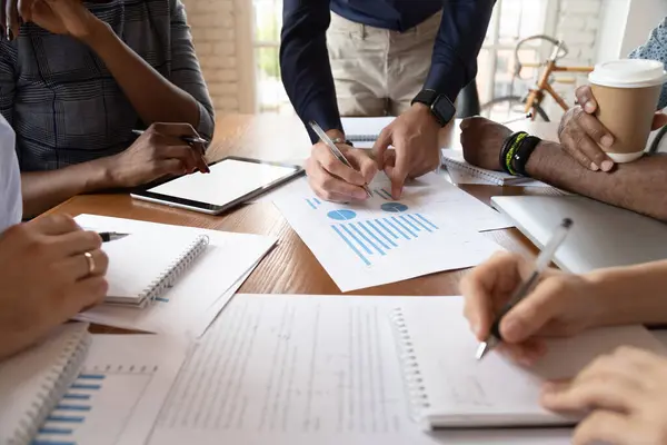 Closeup desk full with papers documents and diverse businesspeople hands — Stock Photo, Image