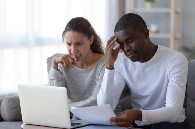 Nervous African American couple checking financial documents, bills