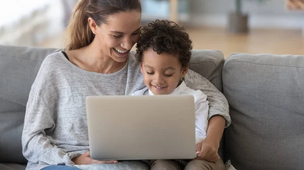 Sonriente madre con hijo afroamericano usando portátil en casa — Foto de Stock