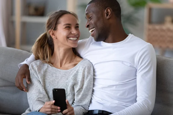 Happy African American couple having fun with phone at home — стокове фото