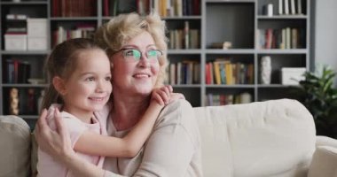 Gülümseyen büyük anne kucaklaşması tatlı torununu korumak için başka tarafa bakıyor.