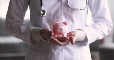 Kadın doktor elleri domuz kumbarası, sağlık hizmeti bağış konsepti