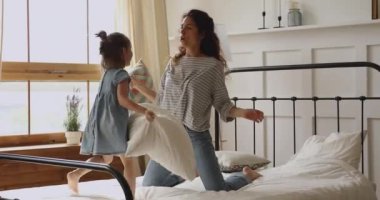 Küçük tatlı kızıyla yastıklarla savaşan mutlu bir anne..