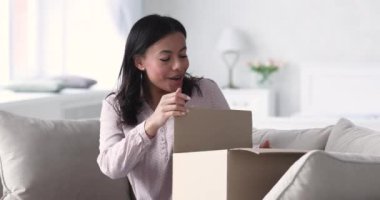 Heyecanlı Afrikalı kadın müşteri. Paket kutusunu aç, kanepeye otur.