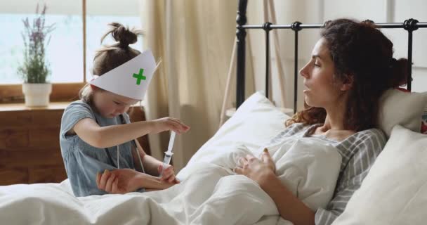 Little girl in medical hat imagining making injection to patient. — Stock video