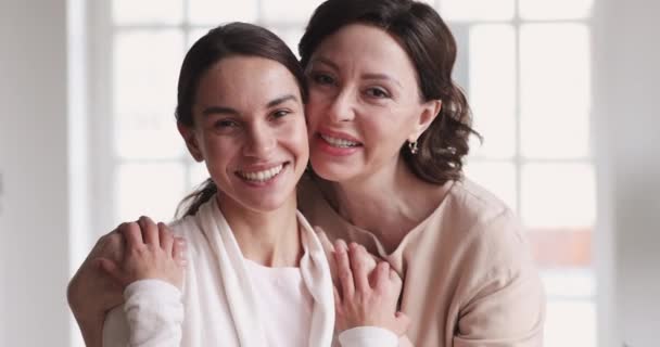 Любящая зрелая мать обнимает молодую дочь наслаждаясь нежностью, портретом — стоковое видео